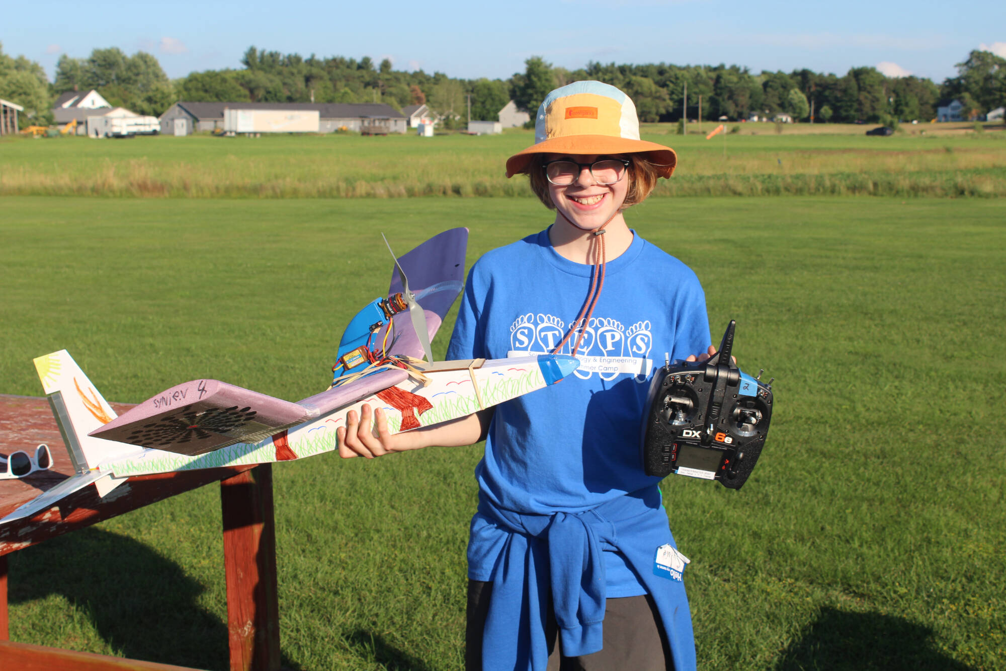 STEPS student holds a plane and controller that they built as part of the camp